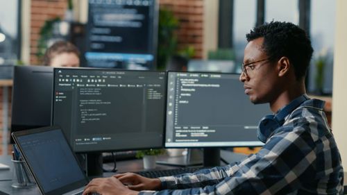 Man working on 2 computer screens